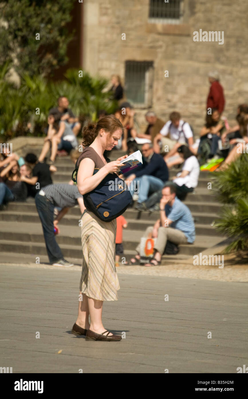 Spanien Barcelona Young Erwachsenfrau für Reisen gekleidet konsultieren Leitfaden Buch stehen im Cathedral plaza Stockfoto