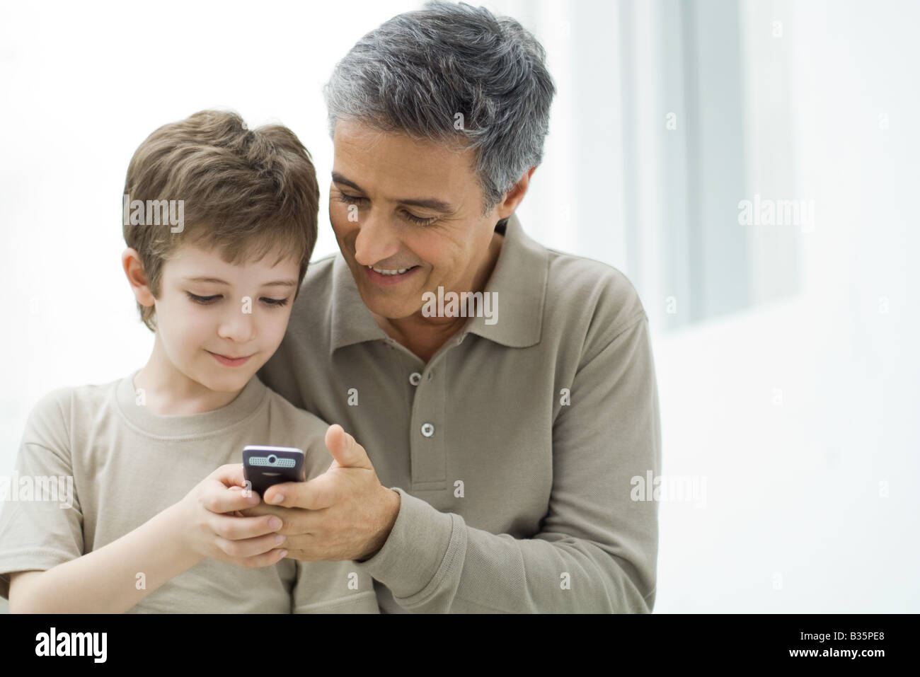 Reifer Mann und seinem kleinen Sohn Blick auf Handy zusammen Stockfoto