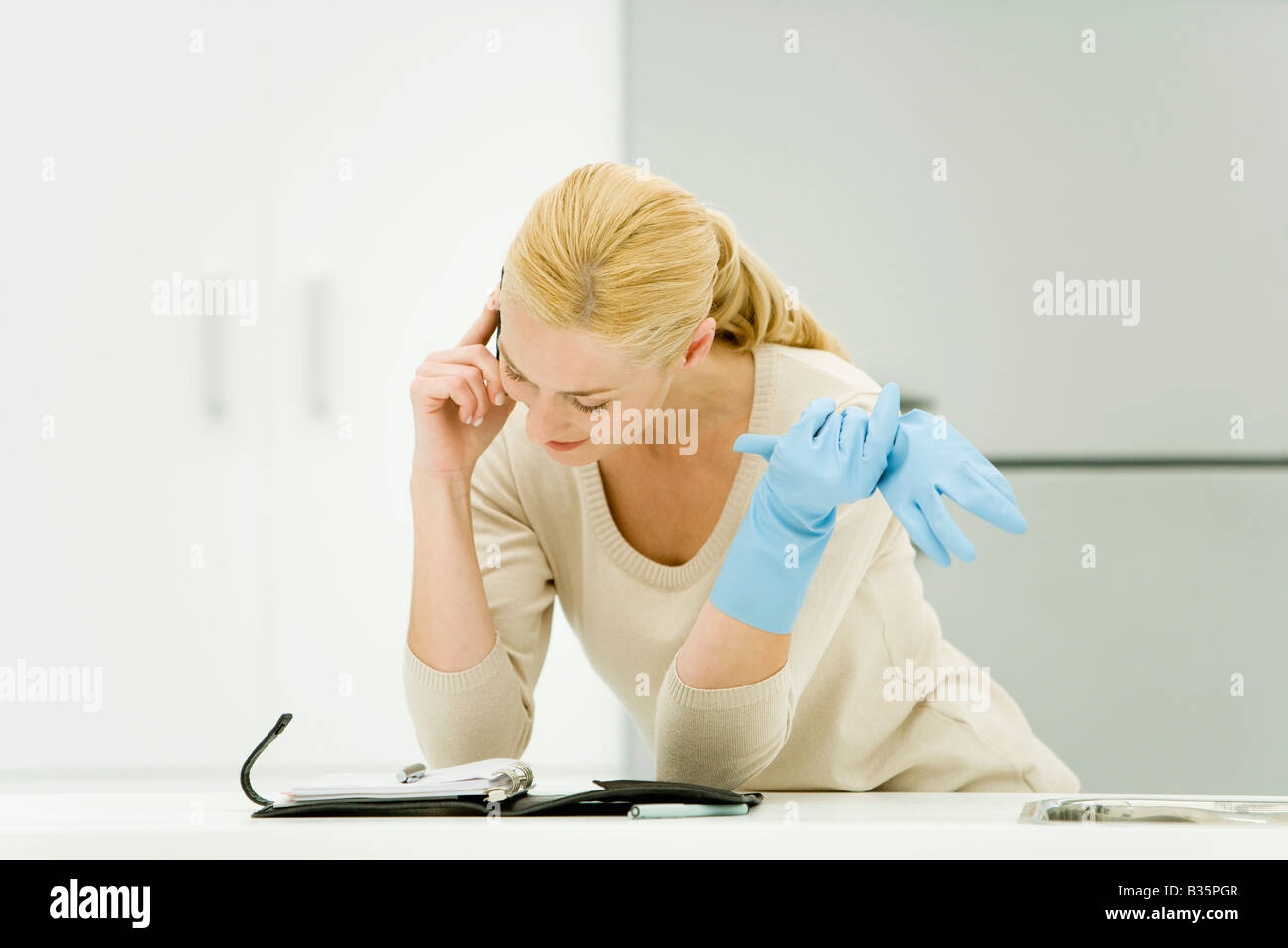 Junge Frau mit Gummihandschuhen, mit Handy und blickte auf die Tagesordnung Stockfoto