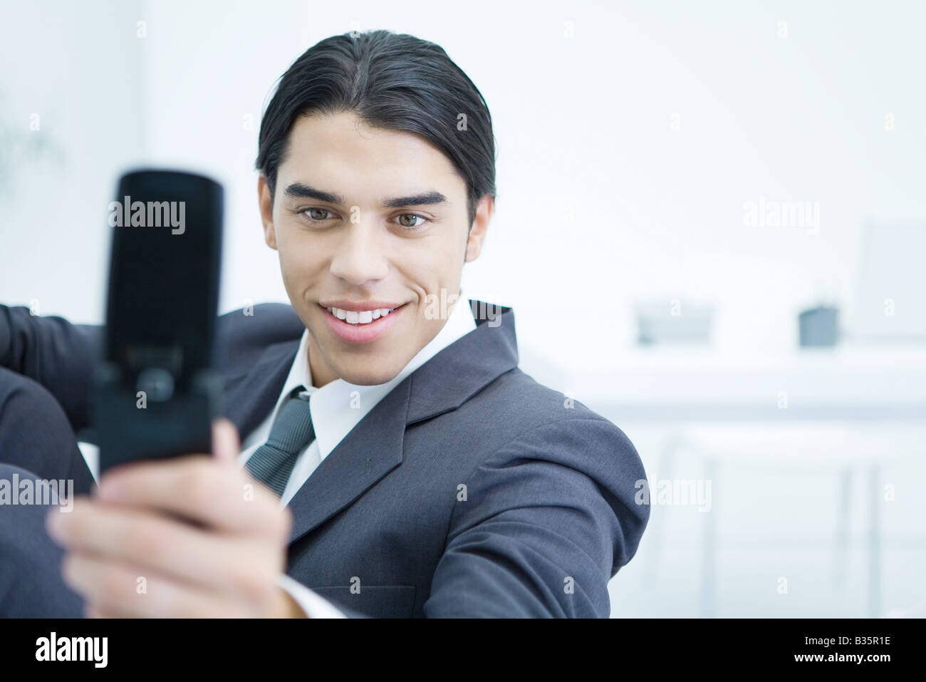 Junger Geschäftsmann mit Handy zum Fotografieren selbst, lächelnd Stockfoto