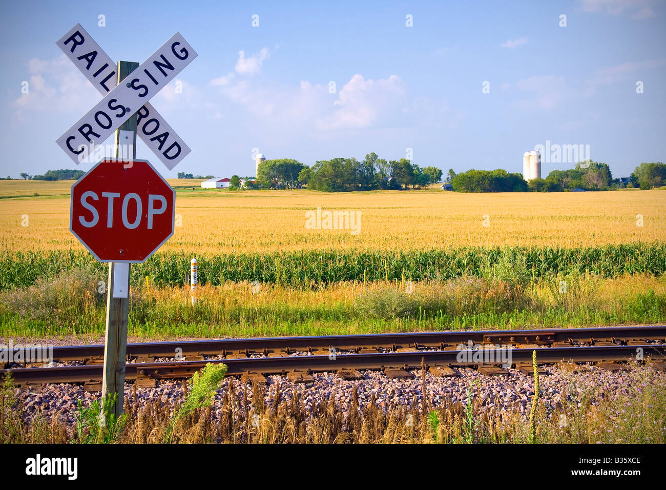 Malerische Bahnübergang in amerikanischen Mitte West mit Bauernhof und Getreide Silo im Hintergrund Stockfoto