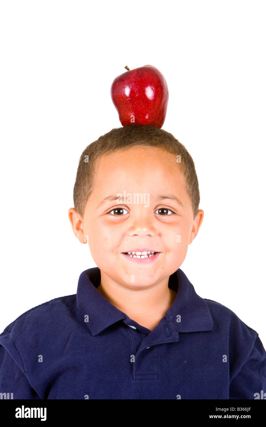 Junge Latino Boy mit einem leuchtend roten Apfel auf den Kopf ausgeglichen Stockfoto
