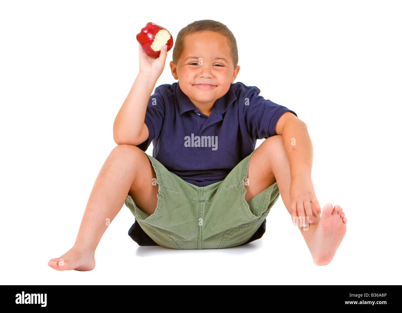 Junge Latino Boy sitzen und halten einen leuchtenden roten Apfel auf dem weißen Hintergrund isoliert Stockfoto