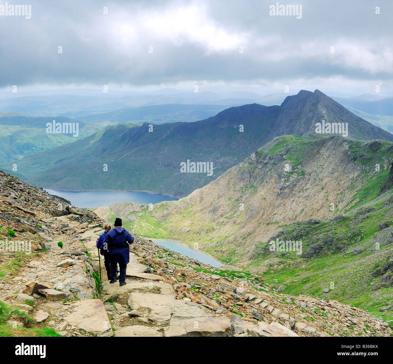 Zwei Menschen, die zu Fuß die Spur in Richtung Llyn Glaslyn und Llyn Llydaw Pyg auf den steilen oberen Hängen des Mount Snowdon Stockfoto
