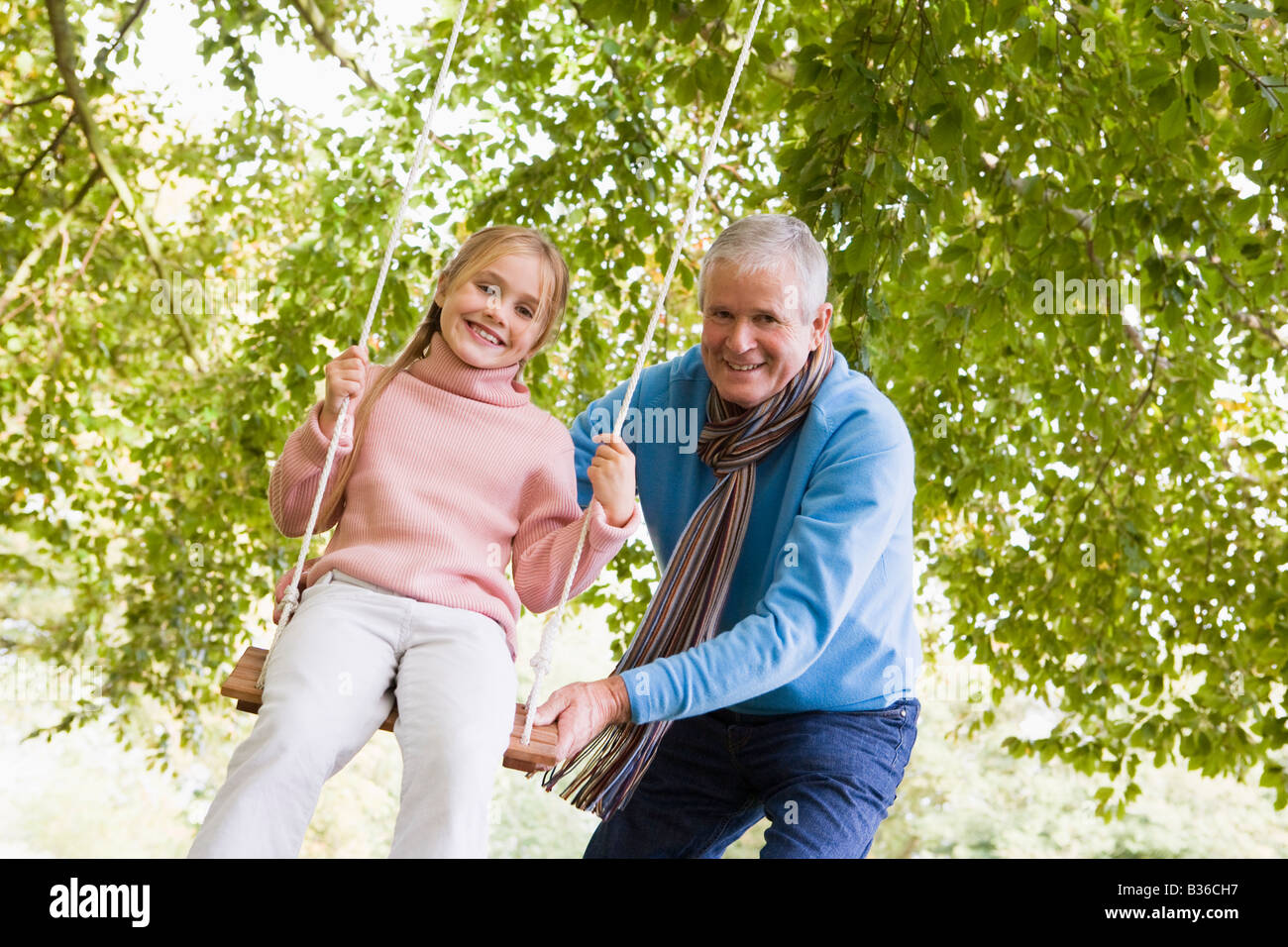 Großvater drängen Enkelin auf Swing und lächelnd (Tiefenschärfe) Stockfoto