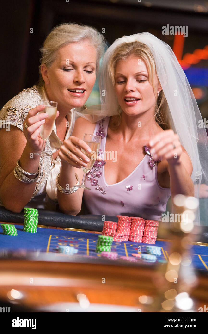 Frau in Brautschleier mit einer anderen Frau im Casino Roulette spielen und Lächeln (Tiefenschärfe) Stockfoto