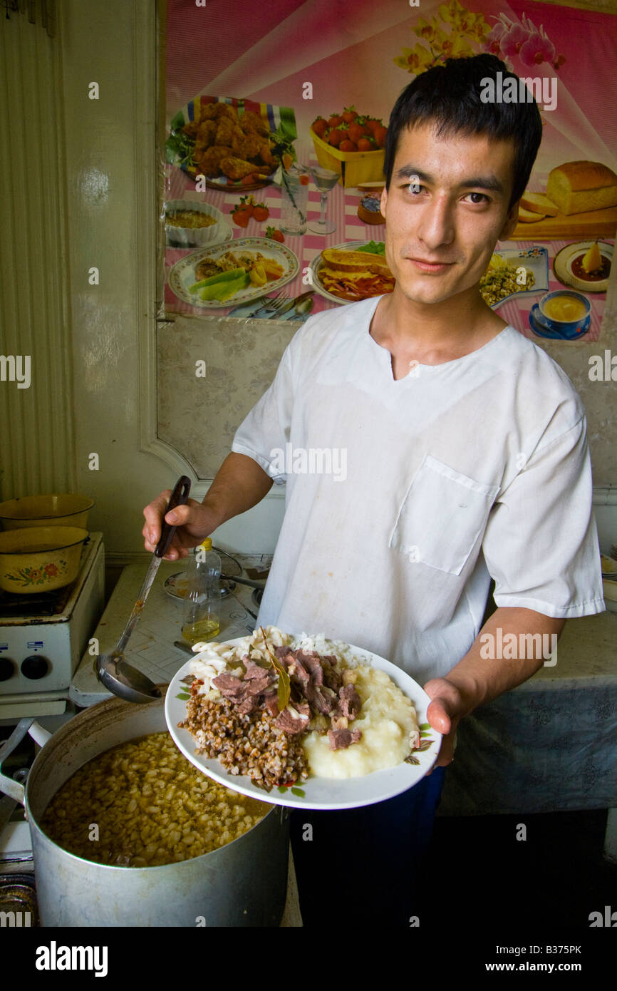 Junge kirgisische Mann dienen Gulasch in einem Restaurant auf dem Markt in Osch Kirgisien Stockfoto