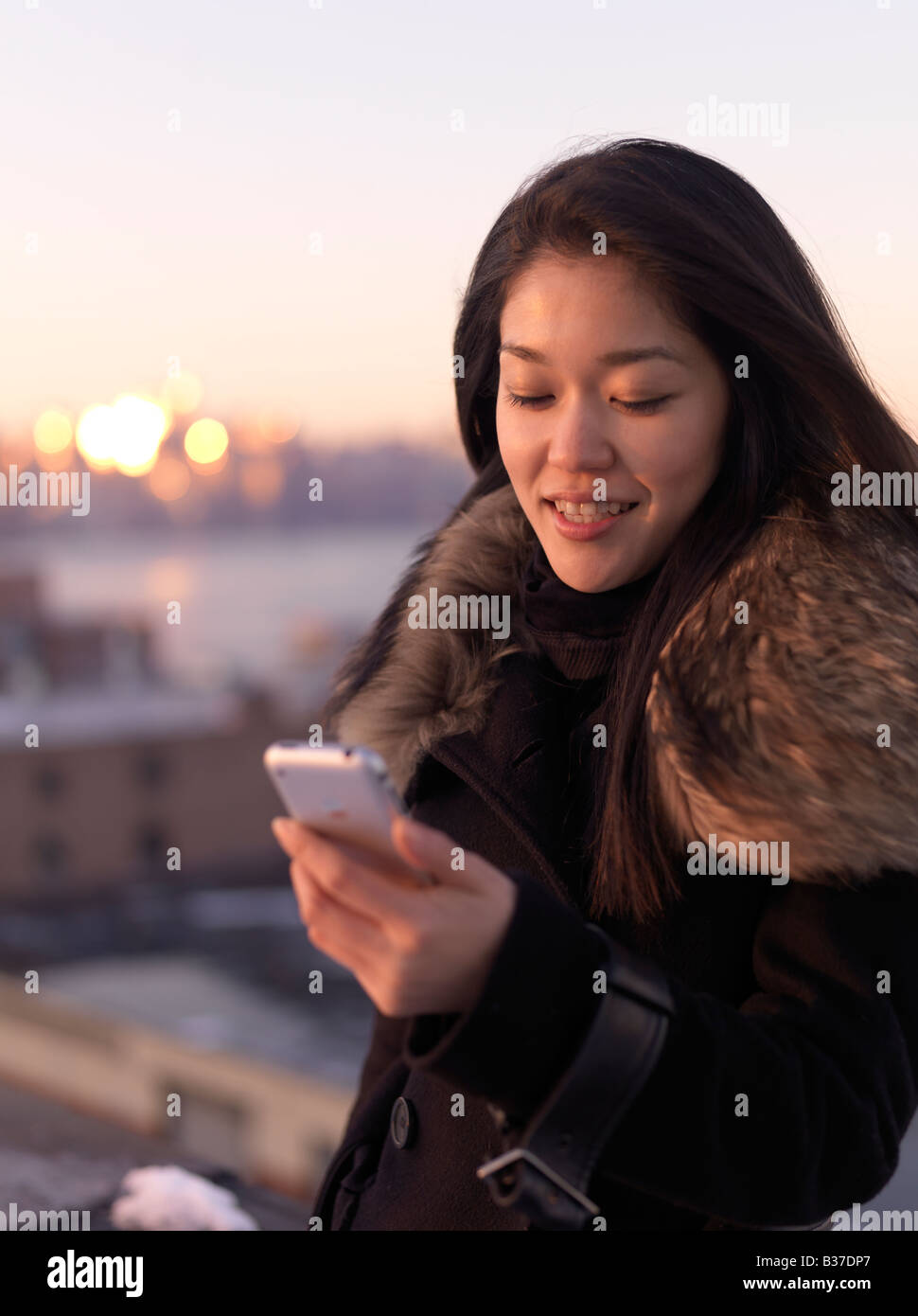 Eine junge Frau liest etwas an ihr Telefon im Freien stehen. Stockfoto