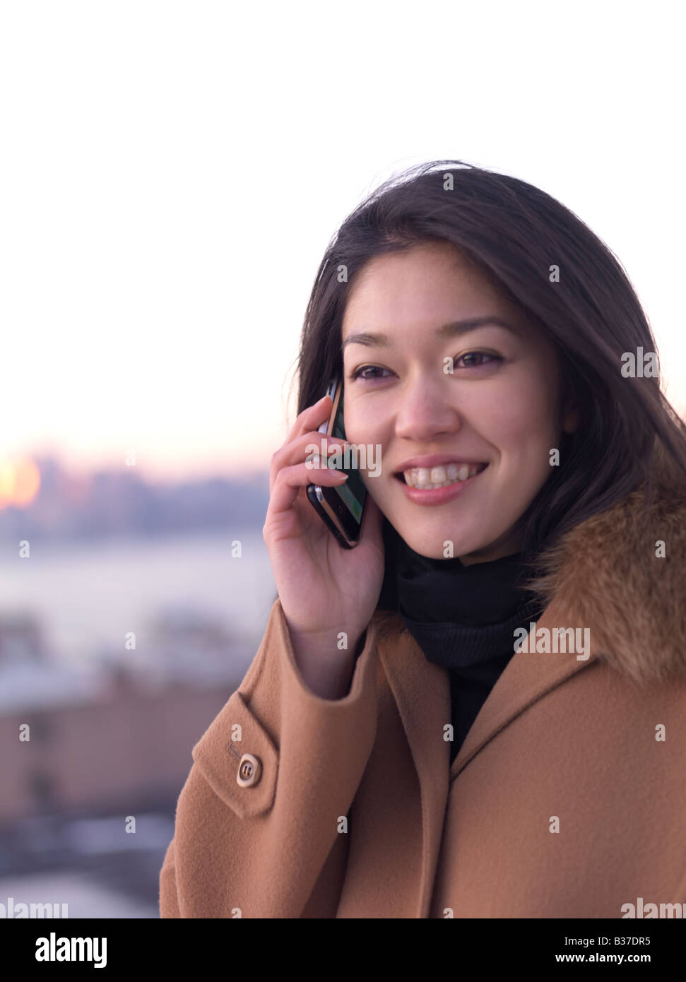 Eine junge Chinesin lächelt, während Sie mit ihrem Handy im Freien. Stockfoto