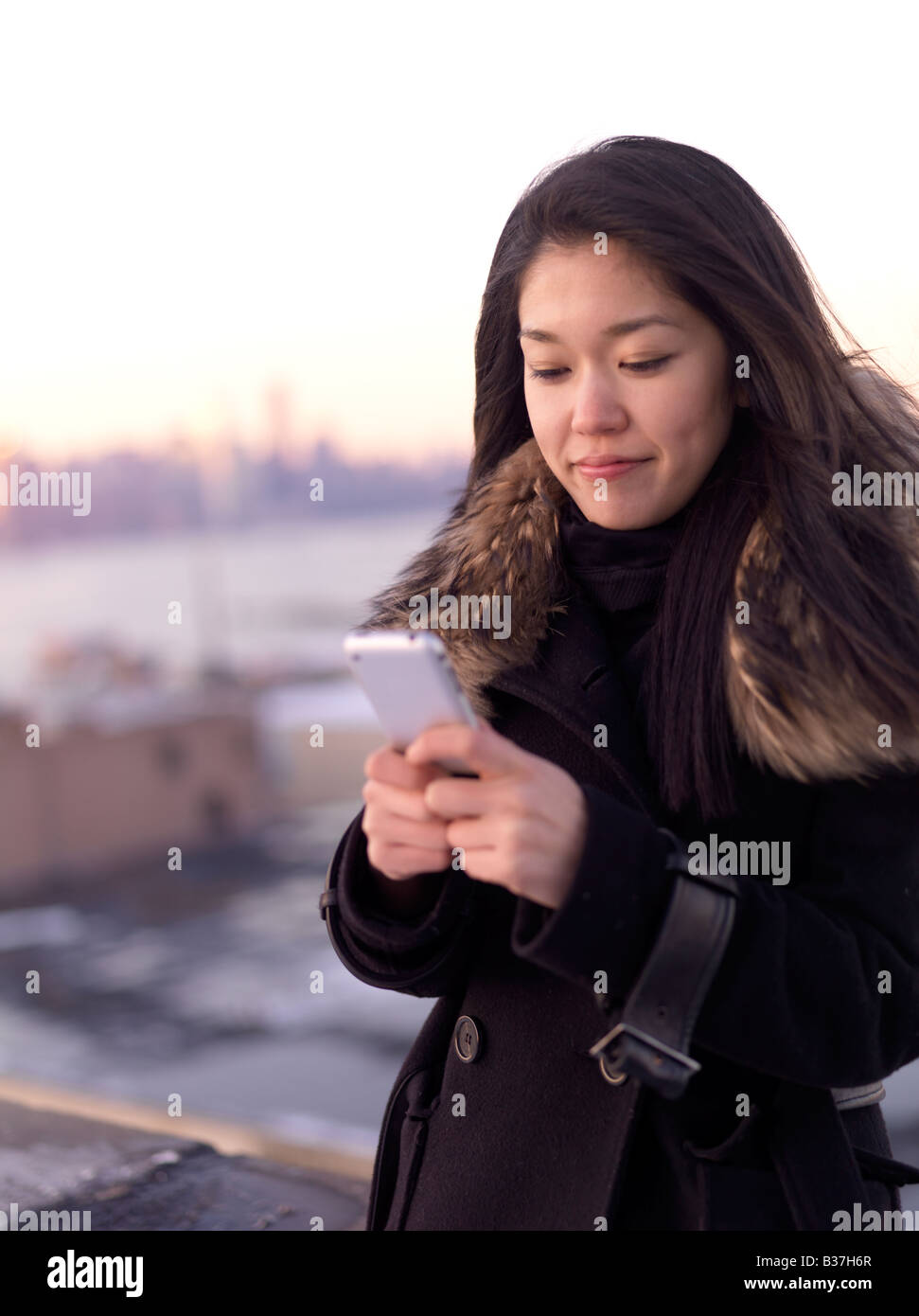 Eine junge Frau liest etwas an ihr Telefon im Freien stehen. Stockfoto