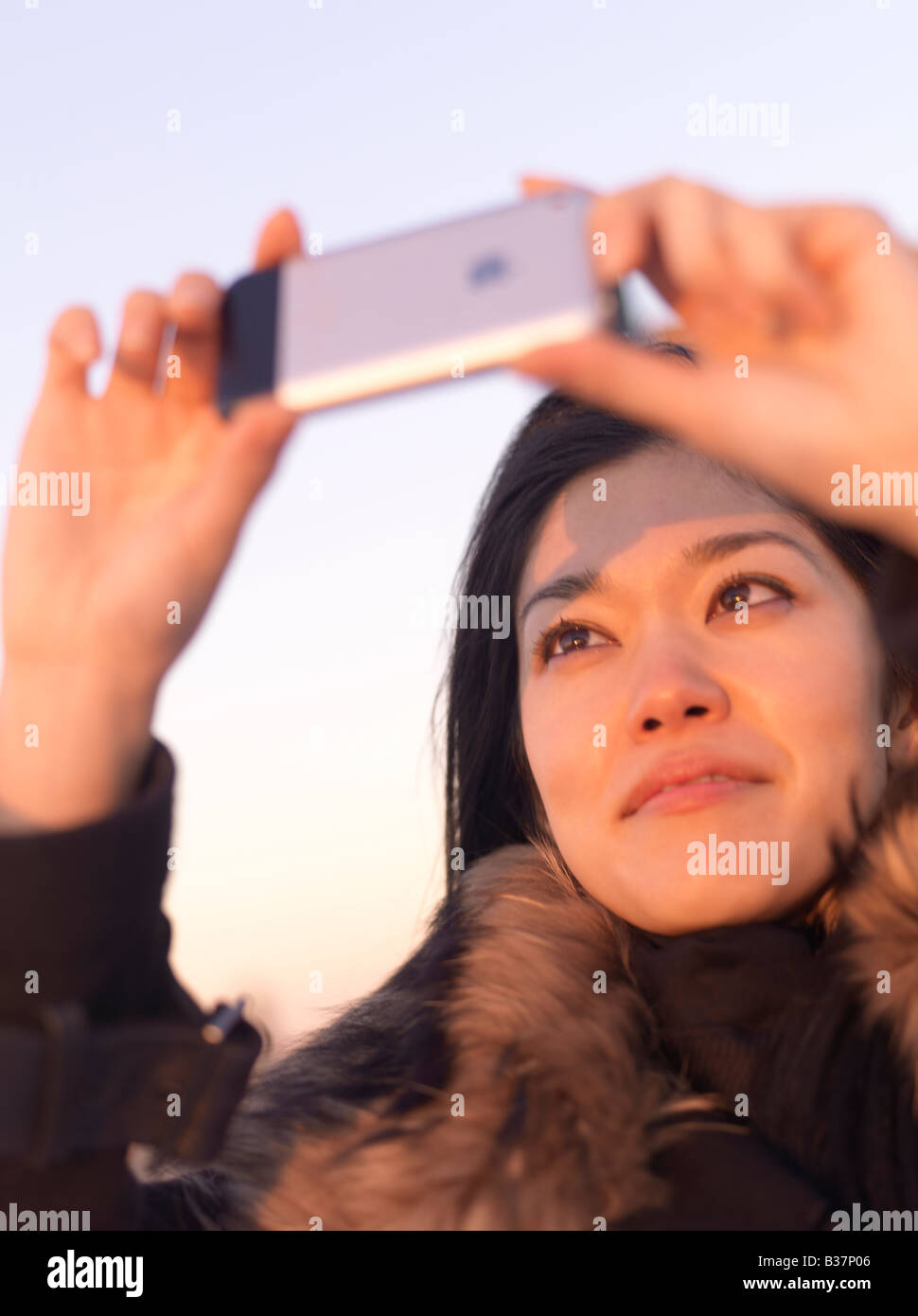 Eine junge Chinesin, die mit ihrem Mobiltelefon um ein Foto aufzunehmen. Stockfoto