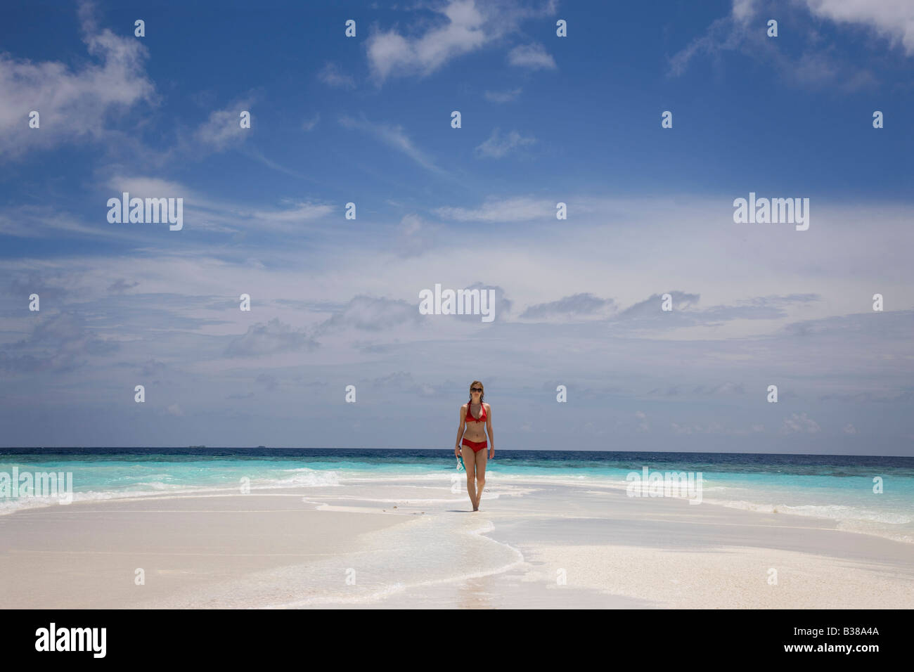 Junge Frau zu Fuß entlang der einsamen weißen Sandstrand, umgeben von tropischen Gewässern auf den Malediven in der Nähe von Indien Stockfoto