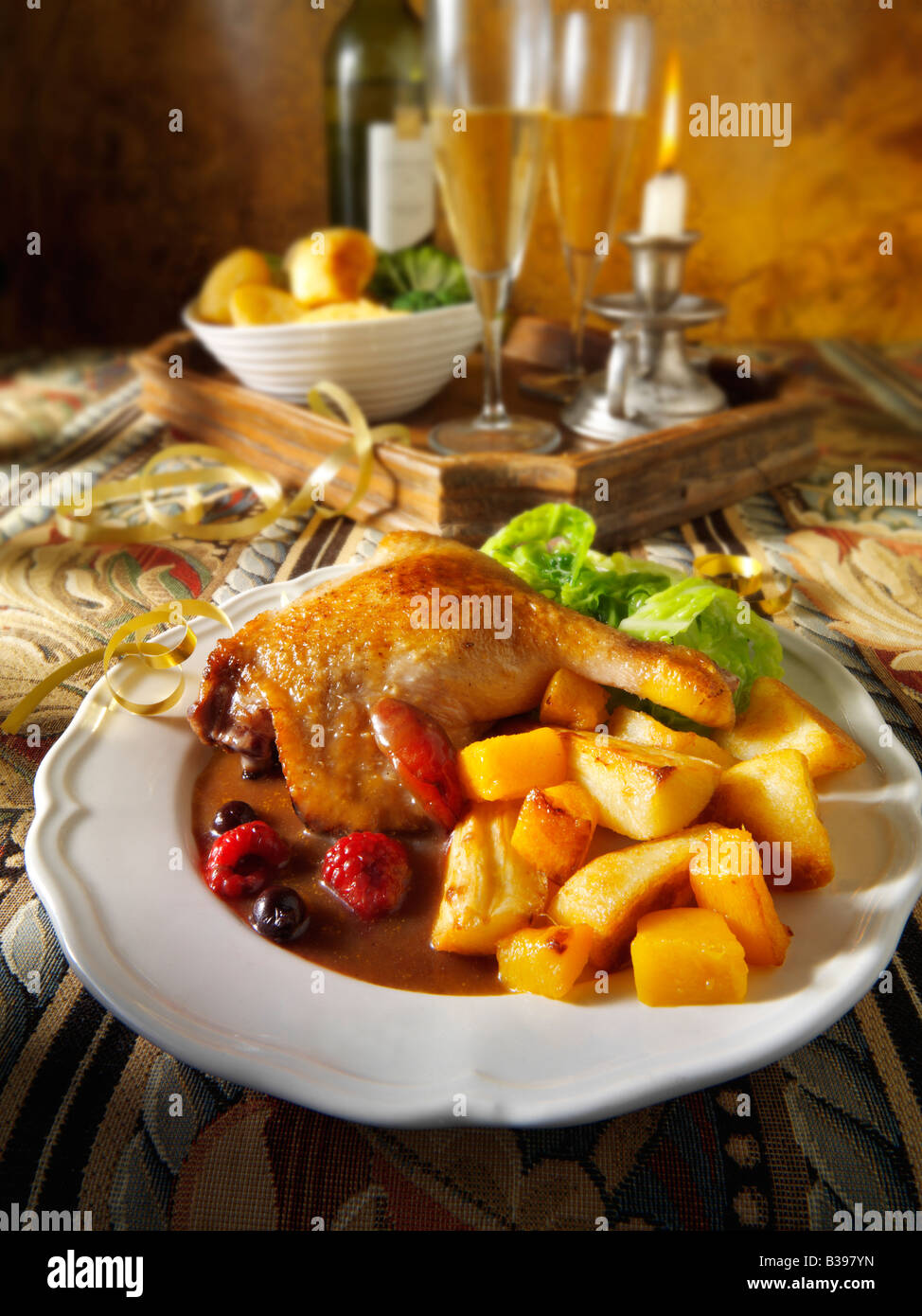 Gebratene Gresham-Entenschenkel serviert mit Winterfruchtsauce, Bratkartoffeln und Gemüse in festlicher Tischstimmung Stockfoto