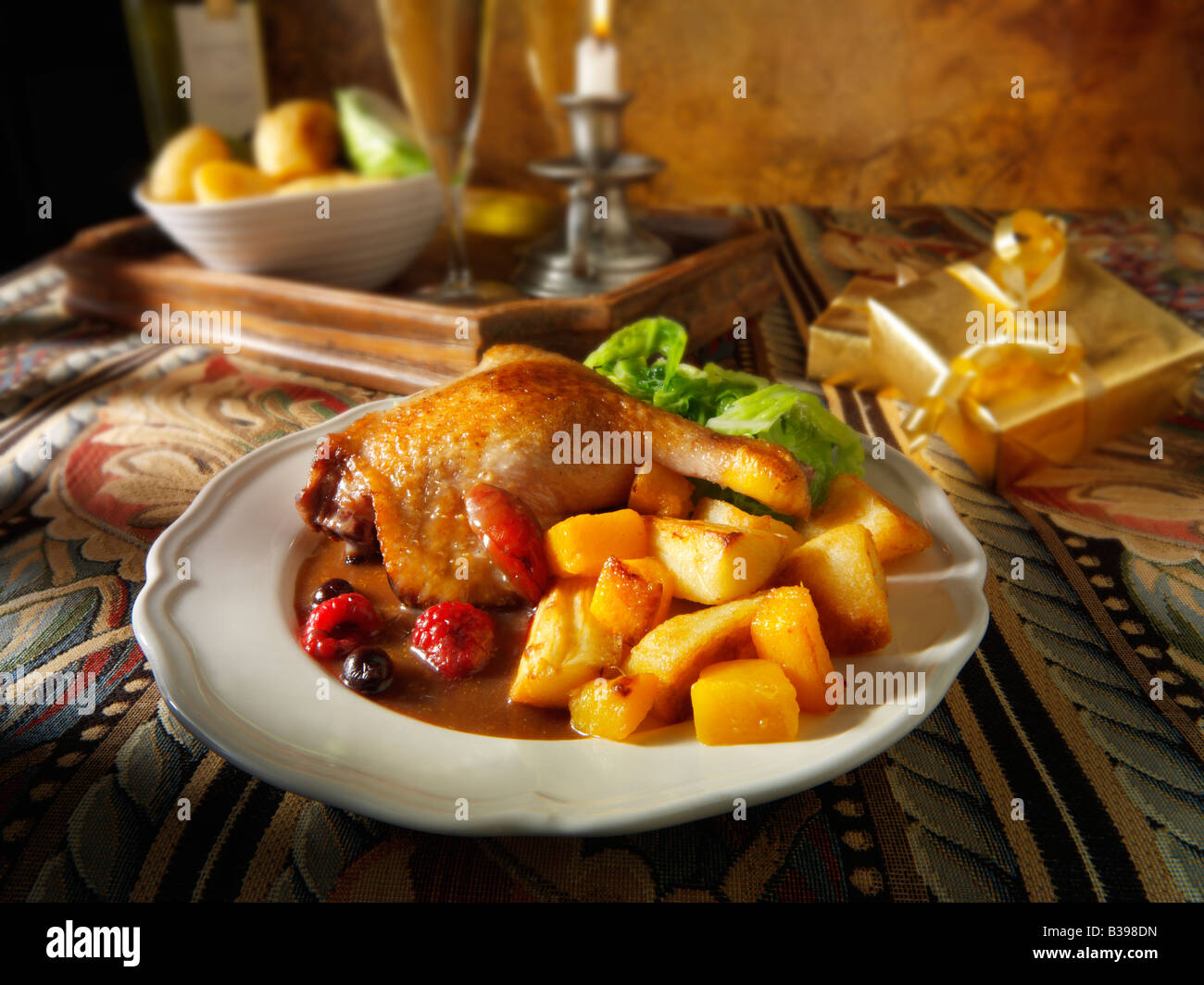 Gebratene Gresham-Entenschenkel serviert mit Winterfruchtsauce, Bratkartoffeln und Gemüse in festlicher Tischstimmung Stockfoto