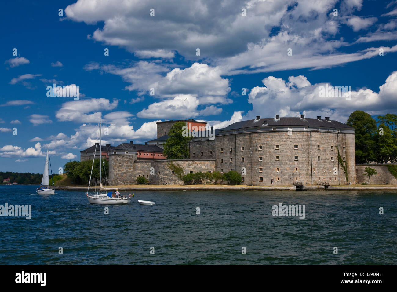 Schweden Sehenswürdigkeiten Attraktion Fort Vaxholms aus Wasser, zwei Segelboote Segeln von schönen Sommernachmittag dimensionale blauer Himmel, geschwollene cumulus Wolken Stockfoto