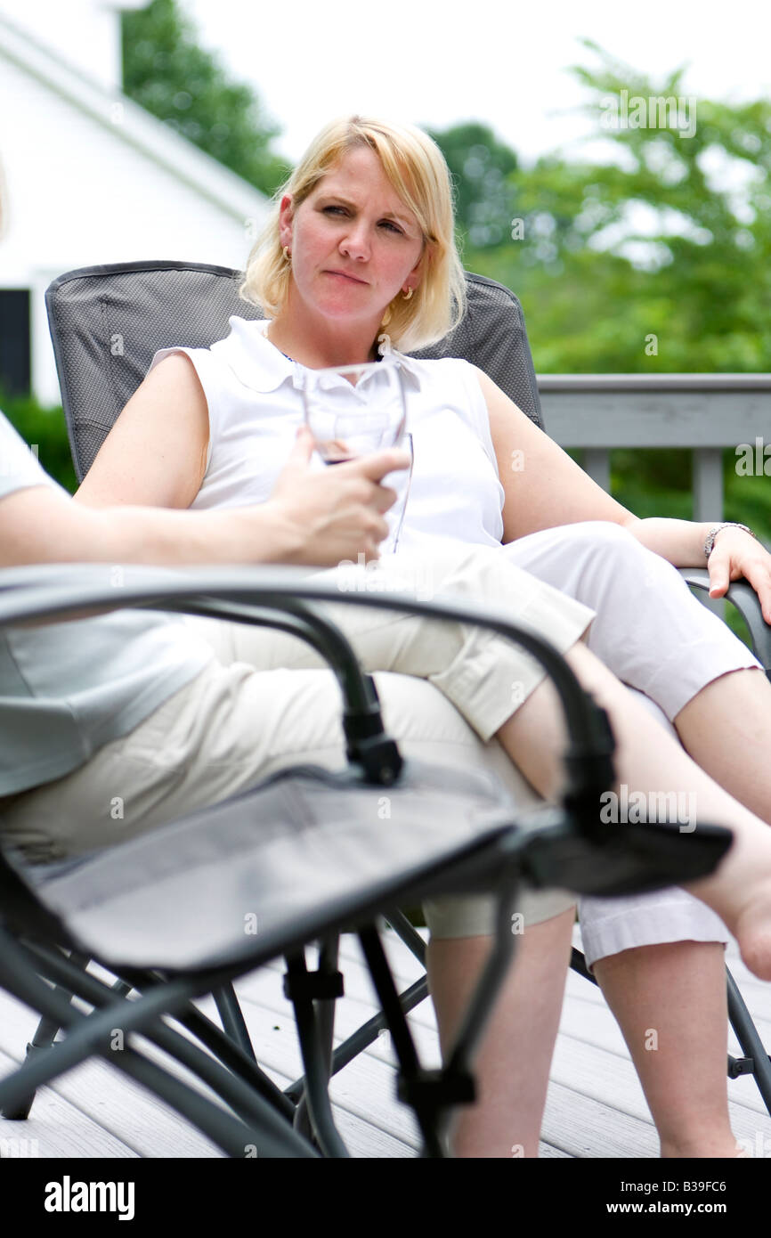 Nachdenkliche blonde Frau draußen sitzen auf einem Stuhl Gespräch anhören Stockfoto