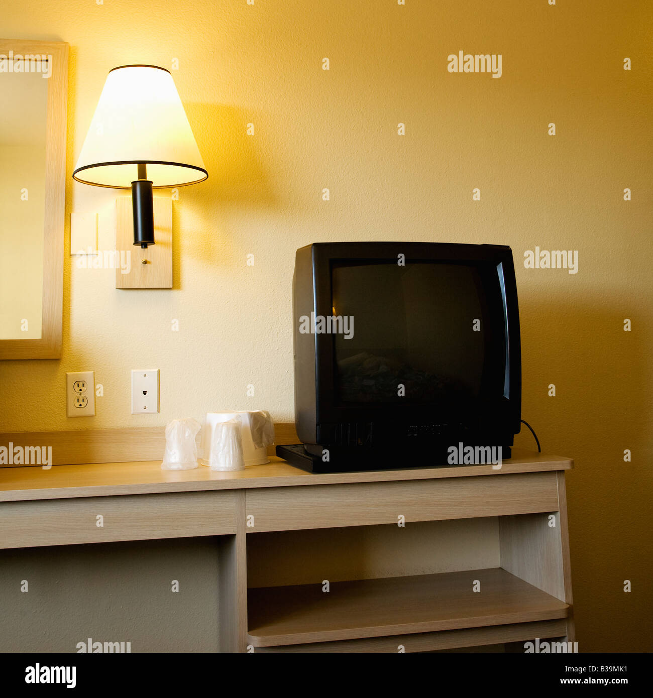 Innenaufnahme der Motel-Zimmer mit TV-Gerät auf dem Nachttisch neben Wandleuchte Stockfoto