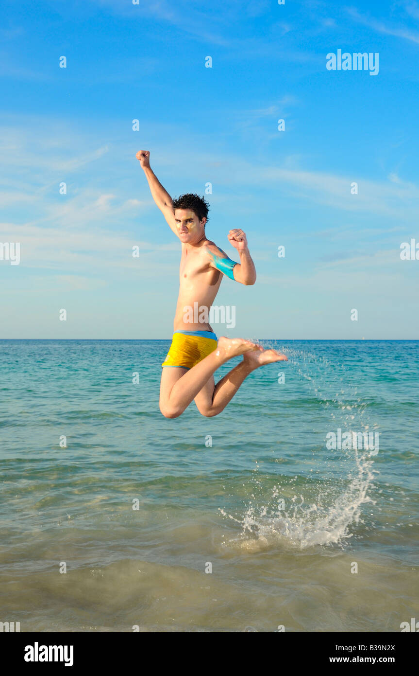 Porträt des jungen männlichen springen der Freude vor tropischen Strand Hintergrund Stockfoto