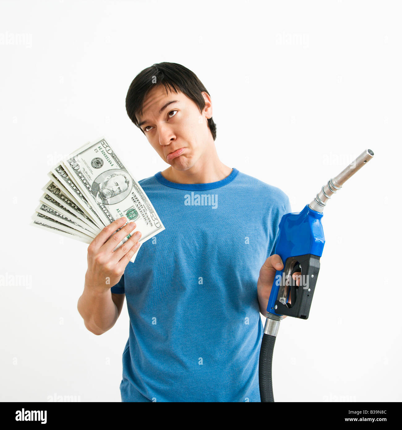 Asiatische junge Mann mit traurigen Ausdruck halten Geld und Gas Pumpe-Düse Stockfoto