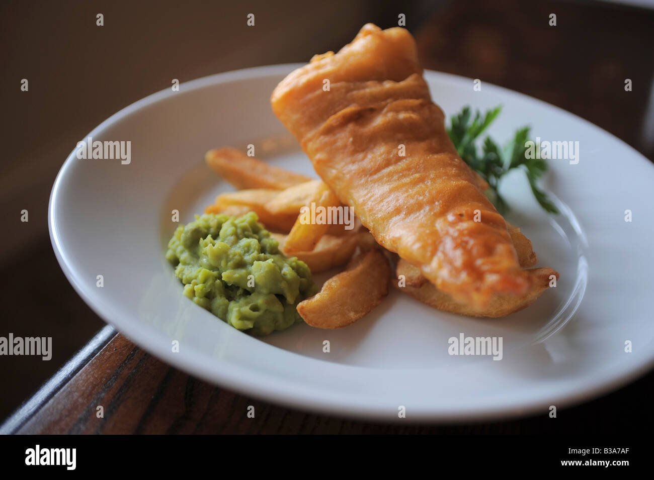 Ein Teller mit Fisch & Chips mit Erbsenpüree Stockfoto
