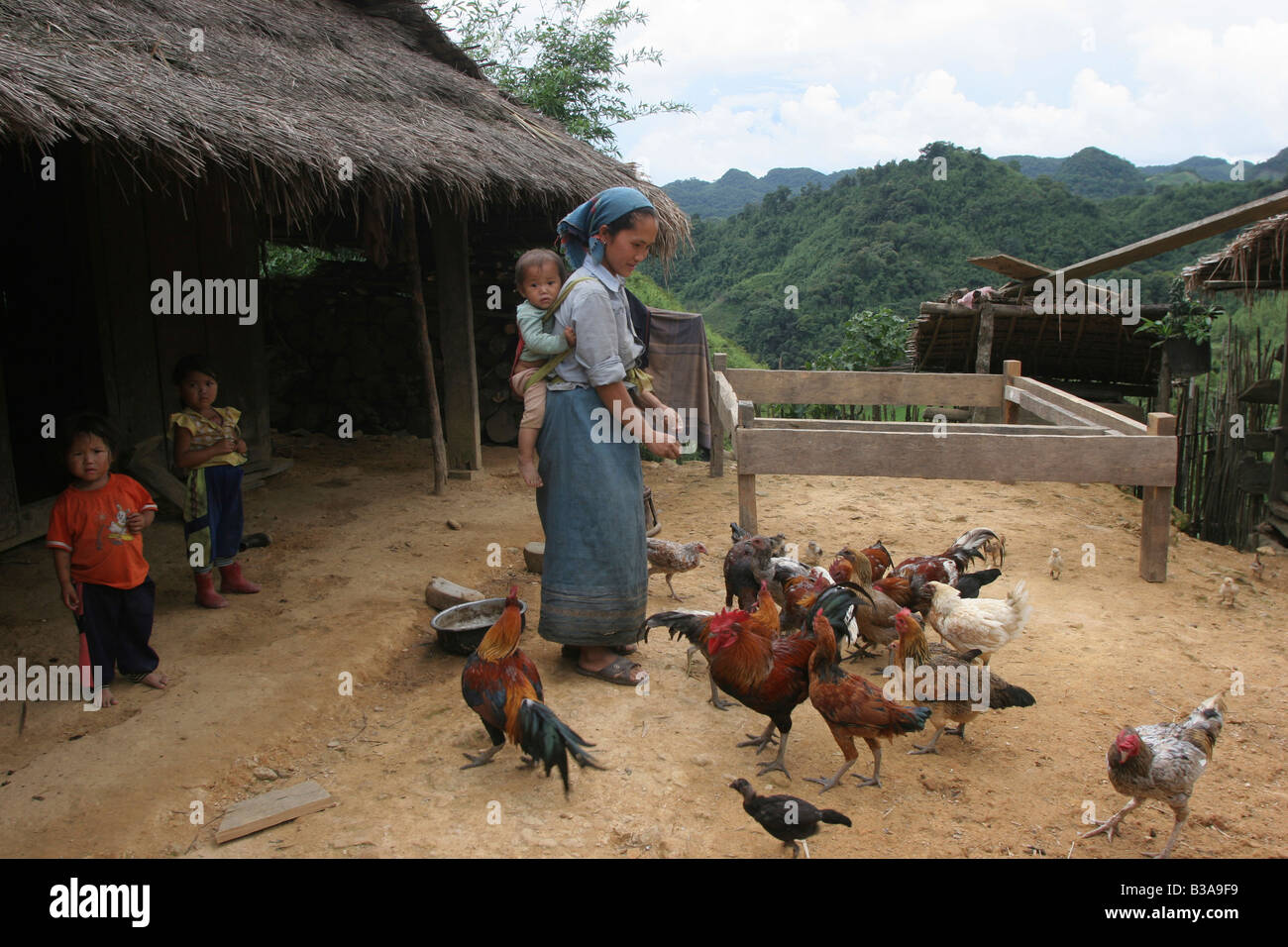 Nong Het District, Provinz Xieng Khouang, Laos. Eine junge Mutter füttert ihr Hühner. Stockfoto