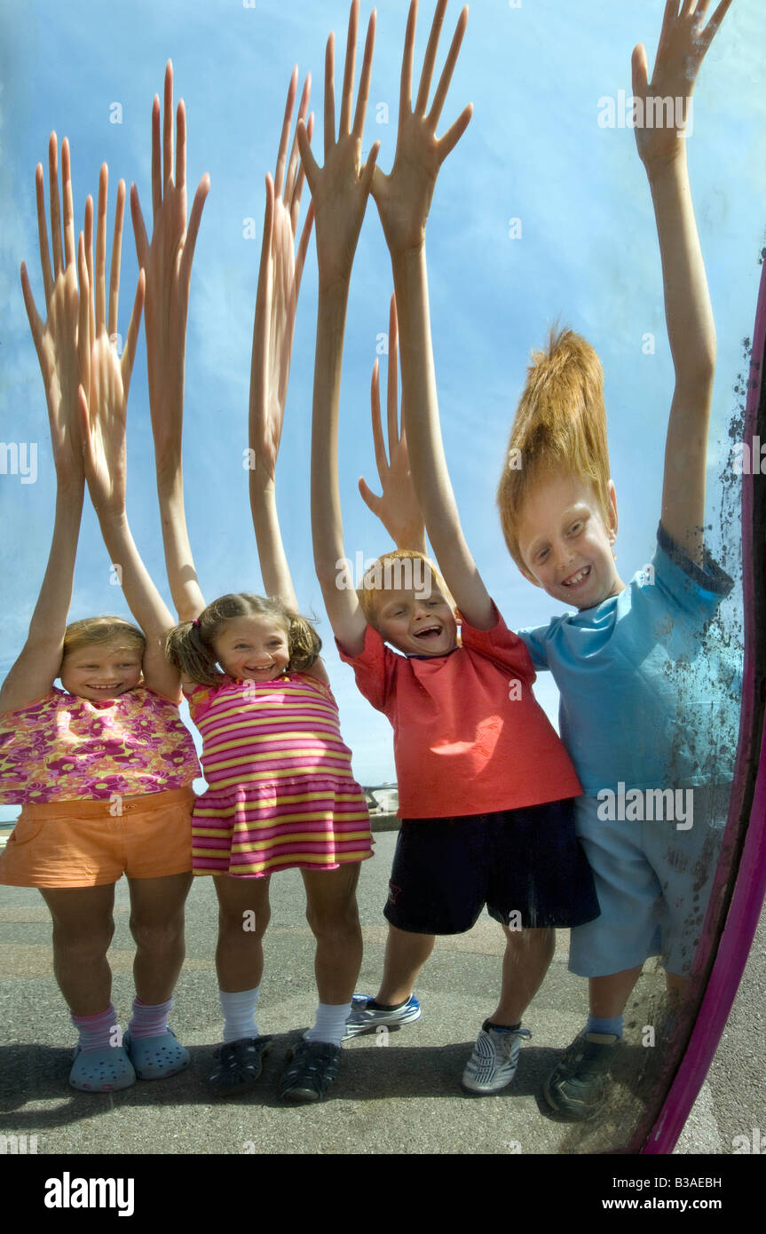 Kinder winken ihr lustige Bilder in einen Zerrspiegel Stockfoto