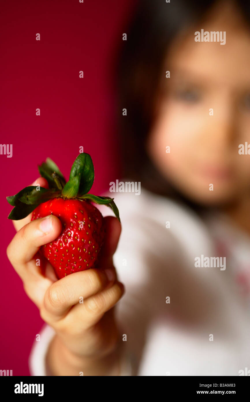 Fünf Jahre altes Mädchen hält Erdbeere Stockfoto