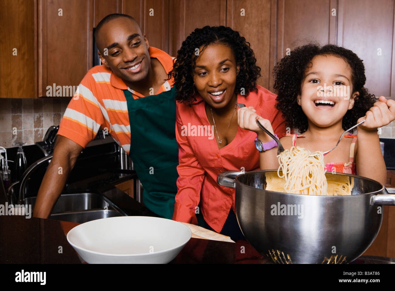 Afrikanische Eltern beobachten Tochter servieren spaghetti Stockfoto