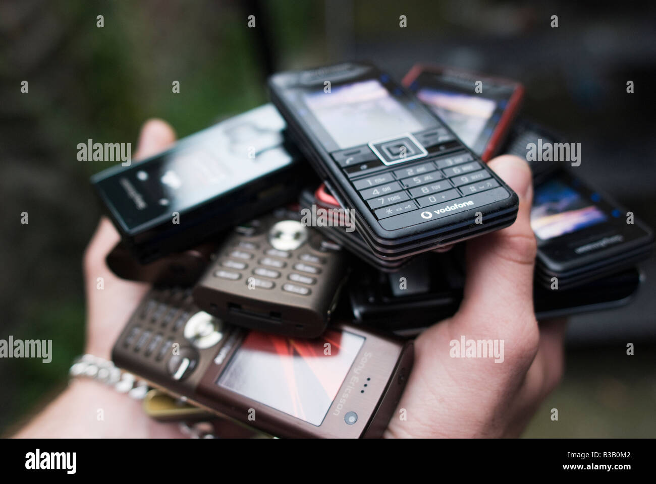 Hände halten einen Haufen von Mobiltelefonen Stockfoto