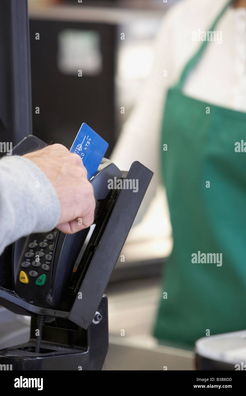 Mann, die Kreditkarte an der Supermarkt Kasse streichen Stockfoto