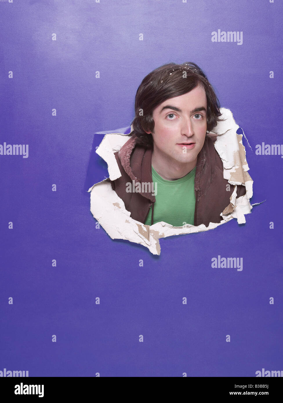 Mann Stossen Kopf durch das Loch in der Wand Stockfoto