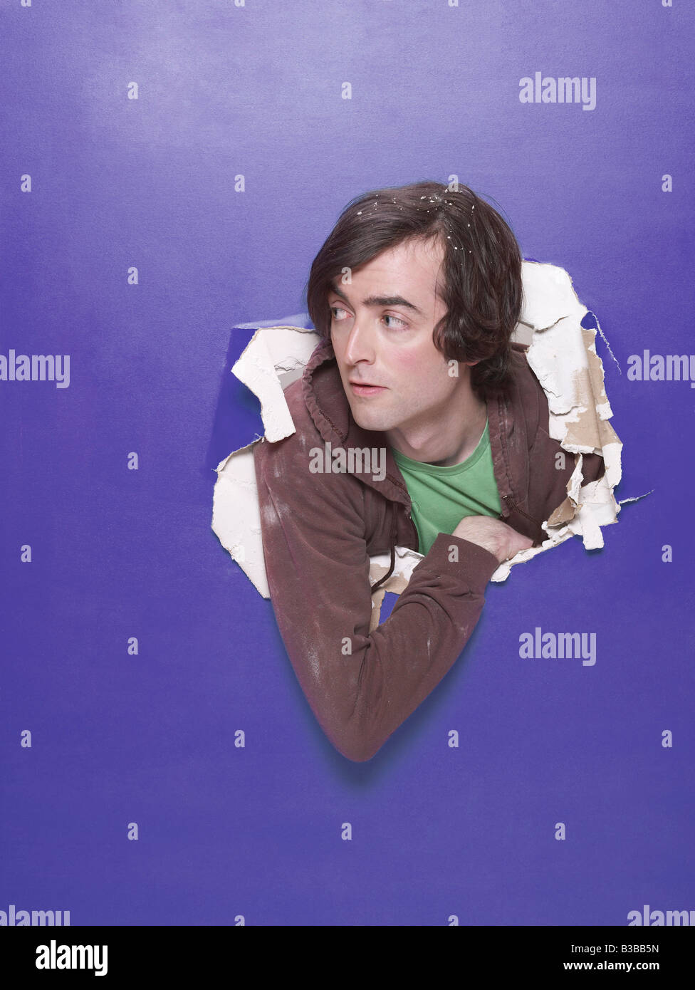 Mann Stossen Kopf durch das Loch in der Wand Stockfoto