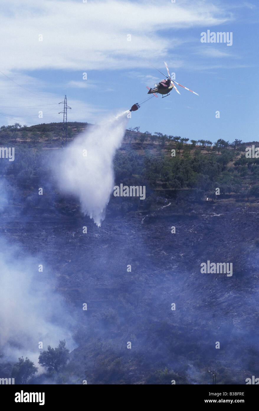 Eine Hubschrauber Wasser Bomben ein Feuer in einem Olivenhain, Spanien. Stockfoto