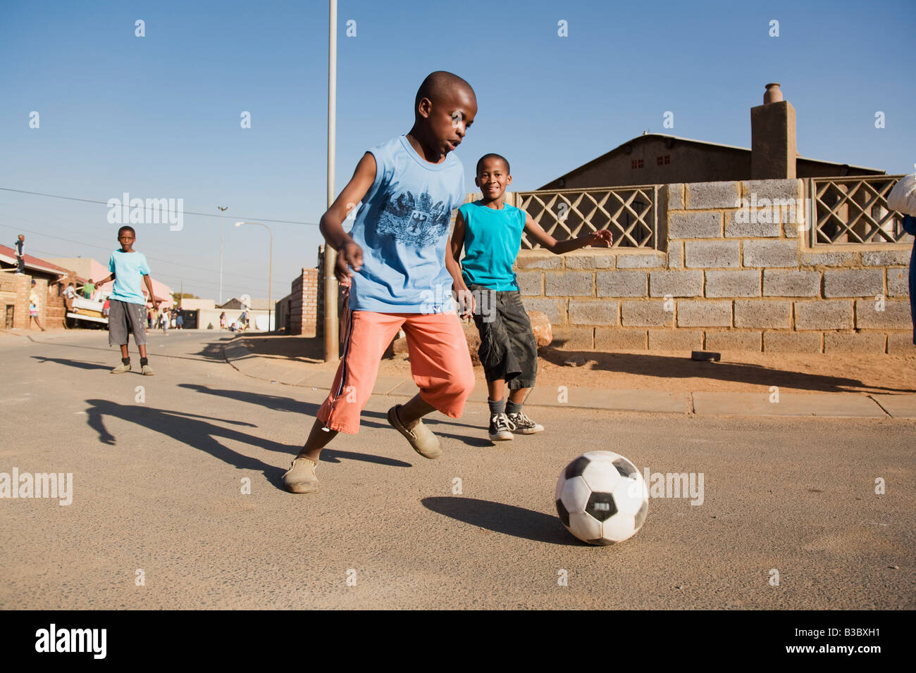 afrikanischen jungen spielen Fußball auf der Straße Stockfoto