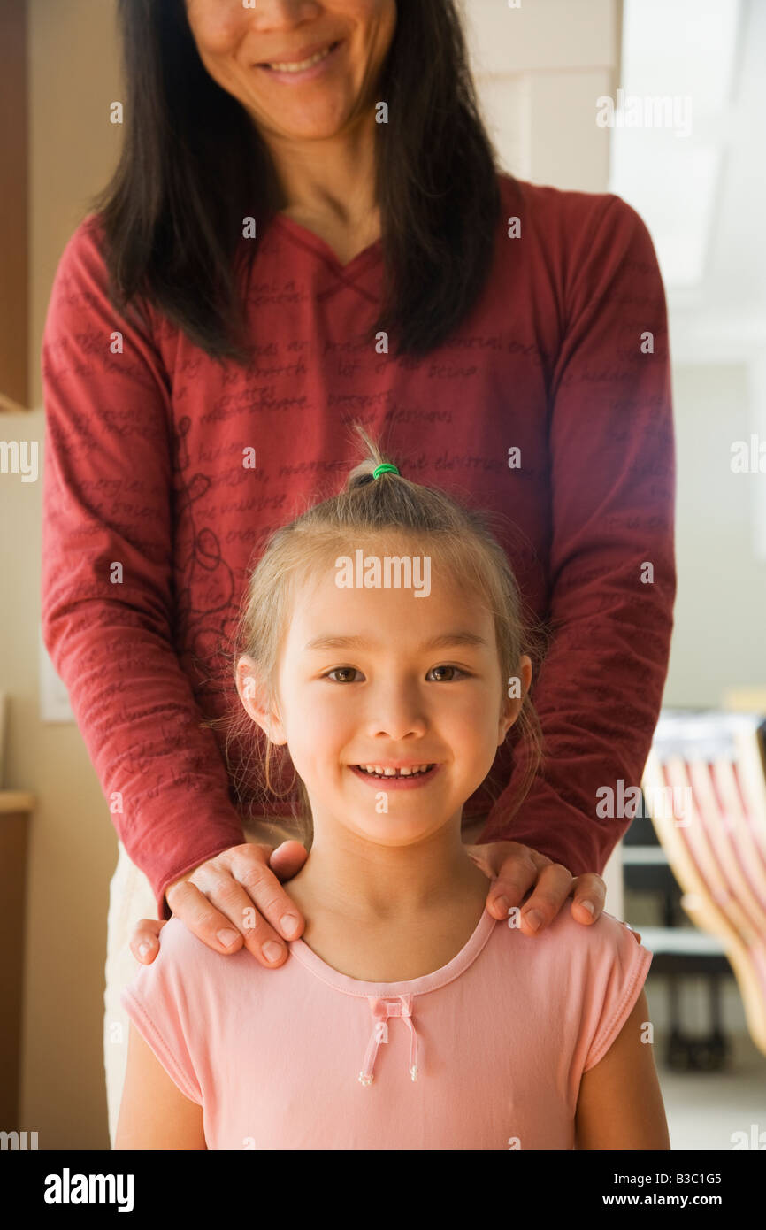 Asiatische Mutter mit den Händen auf den Schultern der Tochter Stockfoto