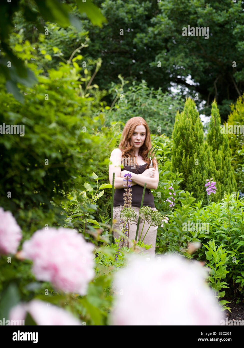 Eine Frau in einem Garten mit verschränkten Armen Stockfoto