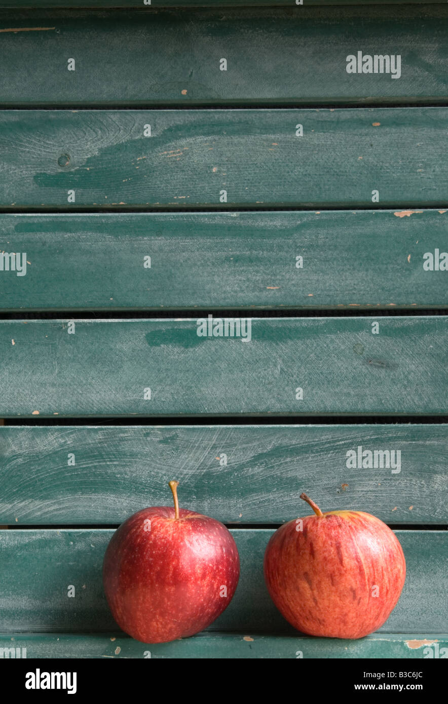Zwei rote Äpfel im Hintergrund blau-grünen Lattenrost aus Holz (Hochformat) Stockfoto