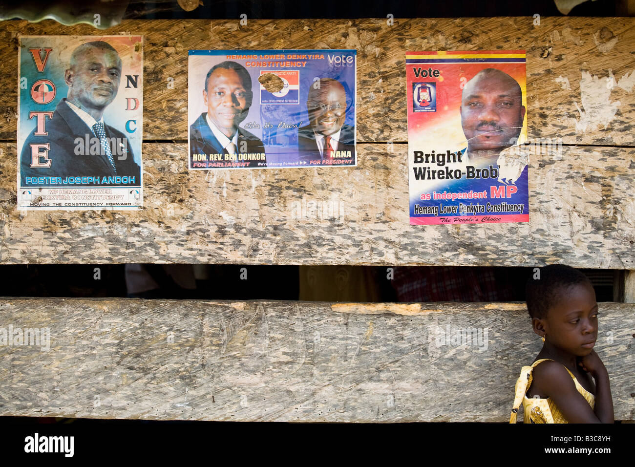 Kind stehend durch eine Wand verputzt mit Plakaten, die Förderung des Präsidenten Gunst, Afiaso, Ghana Stockfoto