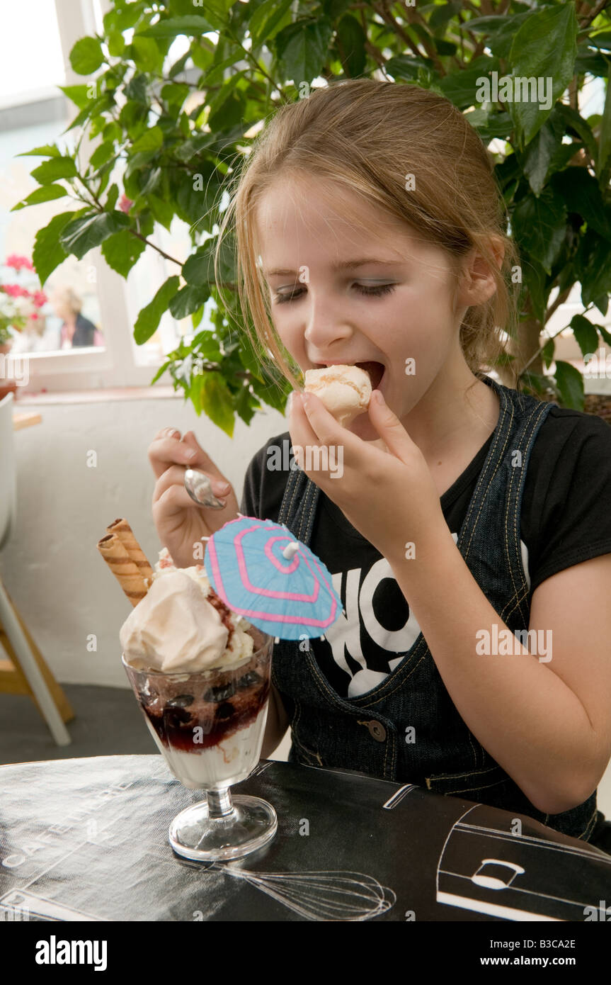10 Jahre altes Mädchen essen einen Eisbecher im Bienenstock auf dem Kai Café Restaurant Aberaeron Wales UK, Sommerurlaub Stockfoto
