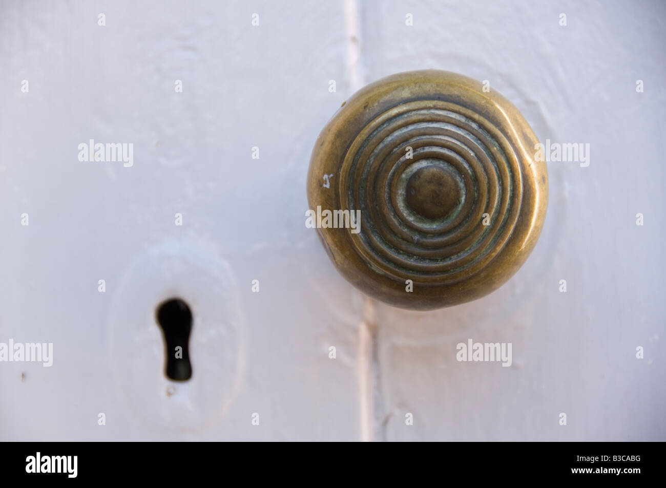 Runde Messing Türklinke auf eine weiße lackierte Tür mit Schlüsselloch Stockfoto