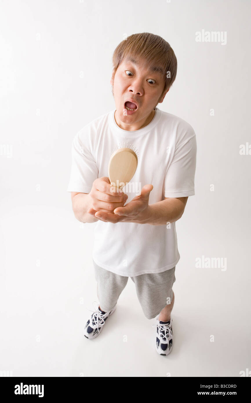 Mitte erwachsenen Mannes betrachten Haarbürste Stockfoto