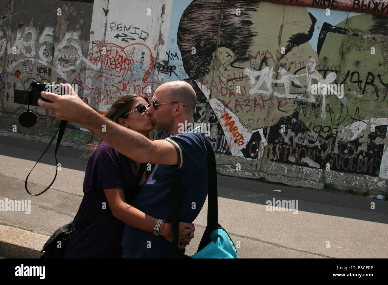 Paar küssen vor Breschnew und Honecker Kuss im Bild auf die Berliner Mauer in der East Side Gallery in Berlin, Deutschland Stockfoto