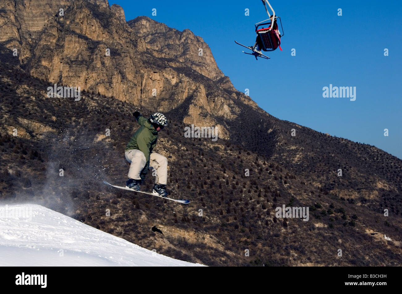 China, Beijing, anderen Skigebiet. Ein Snowboarder springen unter einen Skilift. Stockfoto