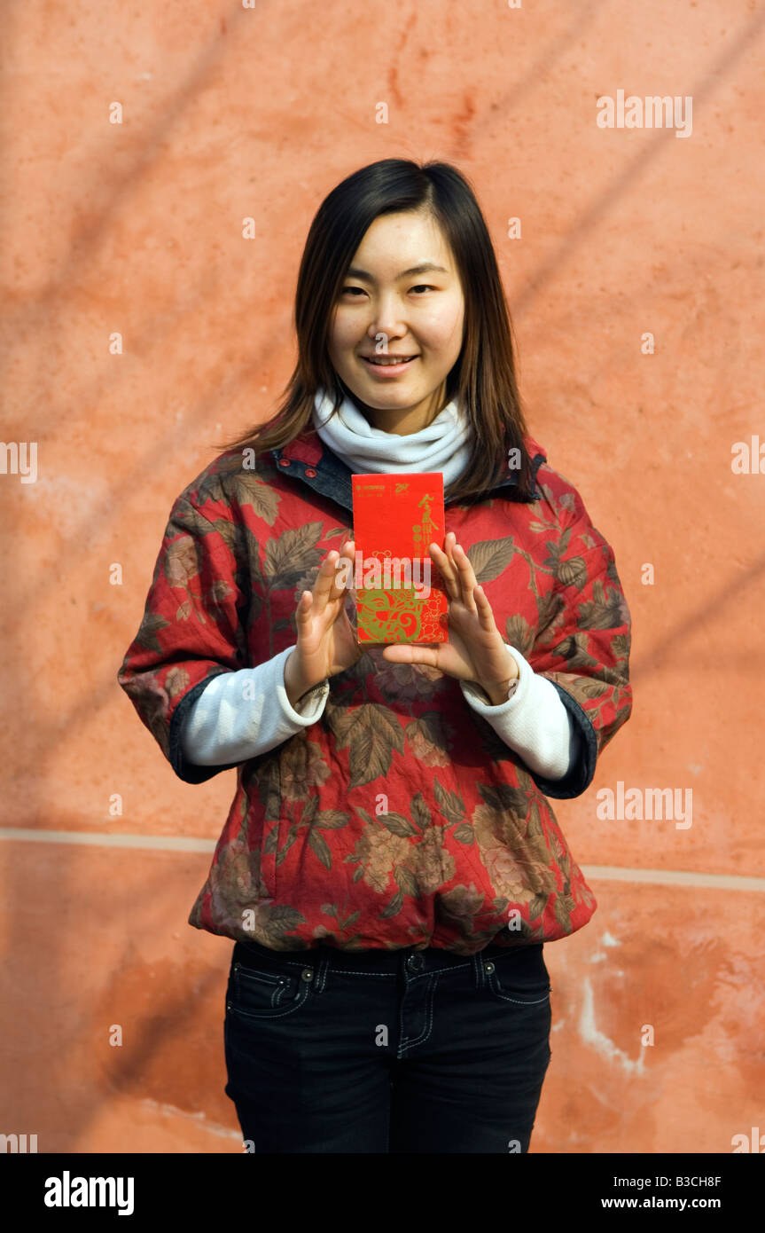 China, Peking. Ein chinesisches Mädchen, traditionellen chinesischen Stil Kleidung hält eine Hongbao Briefumschlag, mit Geld von Schülern und Kindern während Chinese New Year Spring Festival (MR) empfangen wird. Stockfoto
