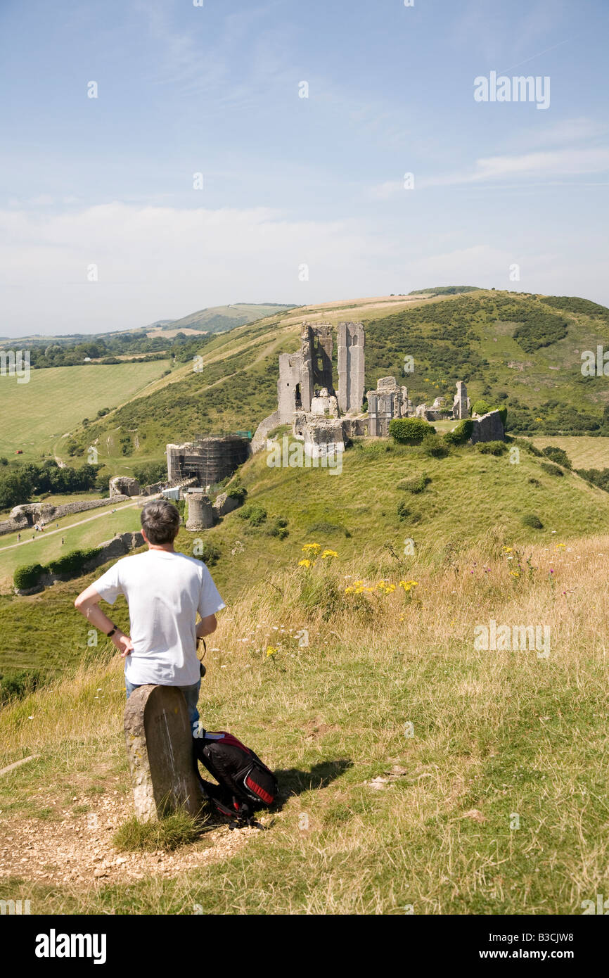 Mann sitzt auf nahe gelegenen Hügel, die Aussicht auf die Ruinen von Corfe Castle Stockfoto