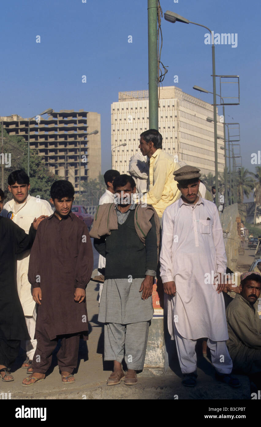 Ethnischen Pashtun Männer auf der Suche nach täglichen Arbeit Line-up an einer Straße-Kreuzung in Karachi, Pakistan Stockfoto
