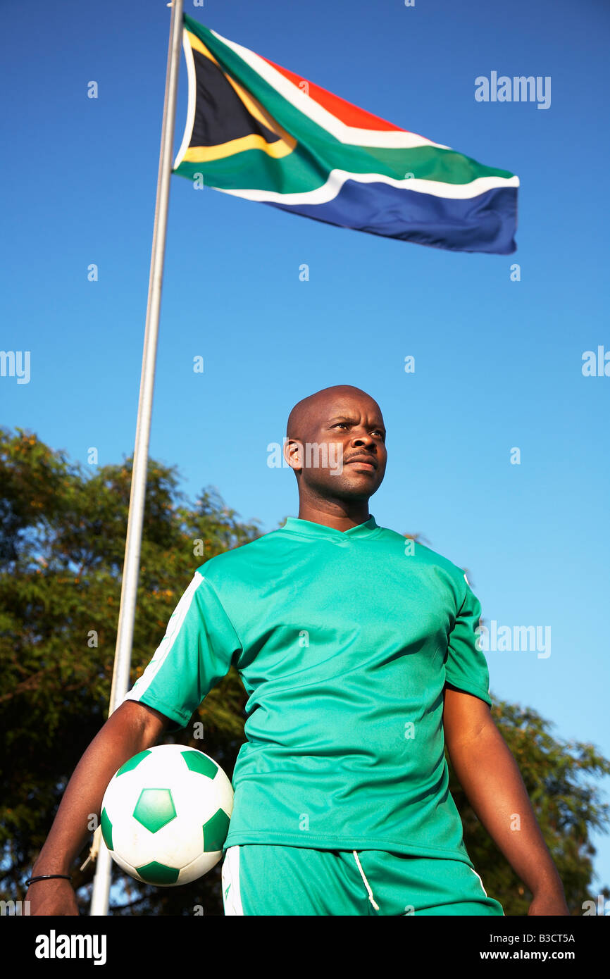 13MA-023 © Monkeyapple aFRIKA Sammlung großer Lager!  Fußballspieler mit Ball unter südafrikanischer Flagge posiert Stockfoto