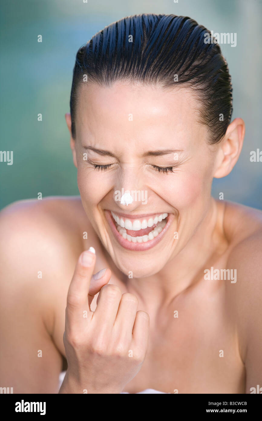 Junge Frau Anwendung Gesichtscreme, Porträt, lachen, Porträt Stockfoto
