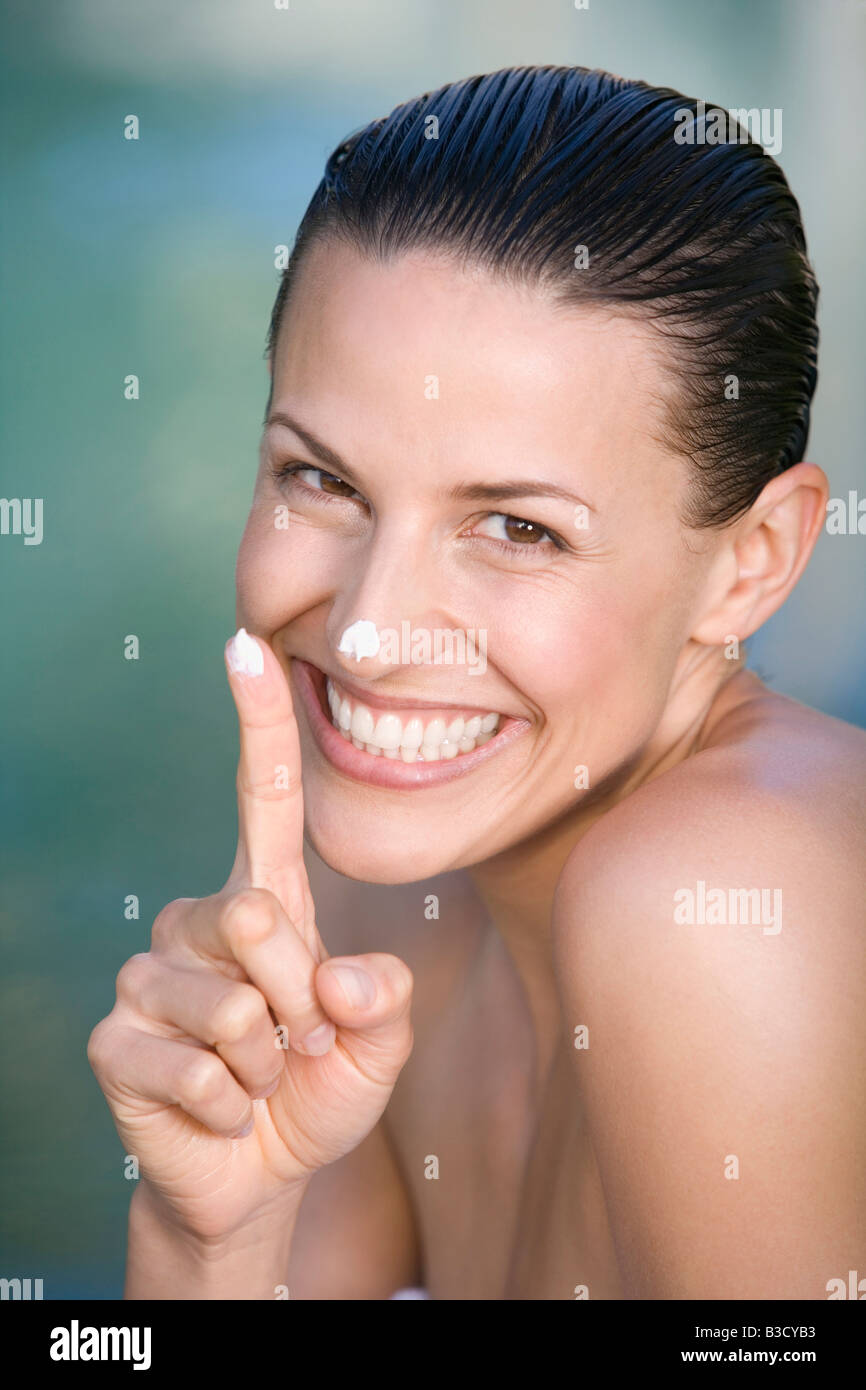 Junge Frau Anwendung Gesichts Creme, Porträt Stockfoto