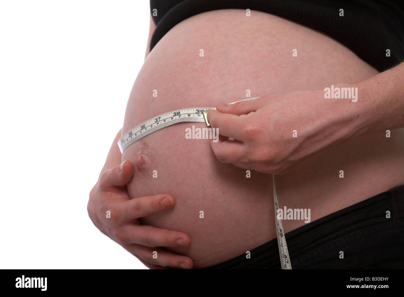 Nahaufnahme von 8 Monat schwanger, Mitte der zwanziger Jahre Frau 25 Jahre alt, die Messung der Babybauch mit Maßband mit Zoll und metrischen Stockfoto